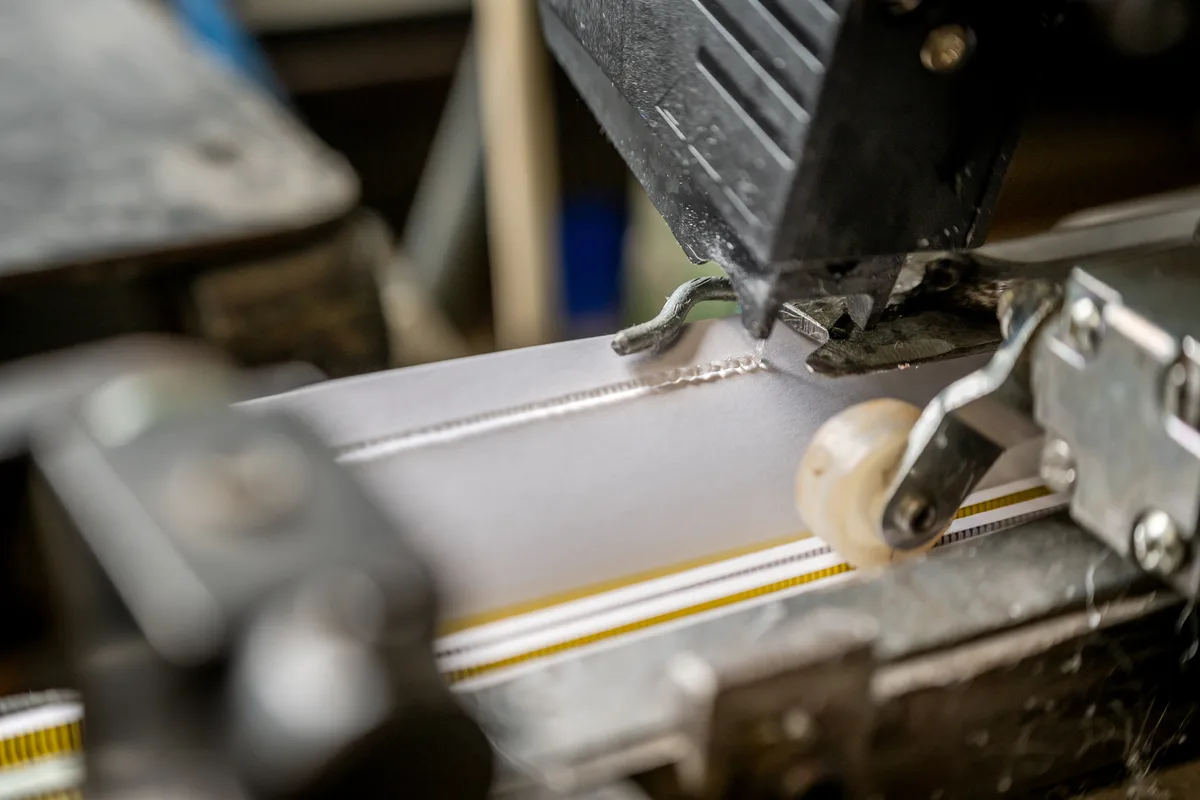 Auftragskopf von Robatech trägt eine Klebstoffraupe auf eine Papiermanschette auf